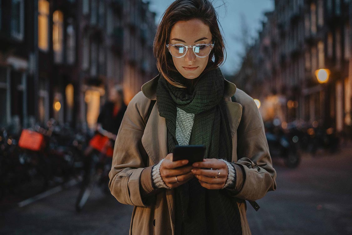 Woman purchasing makeup with her mobile device on her walk home from work