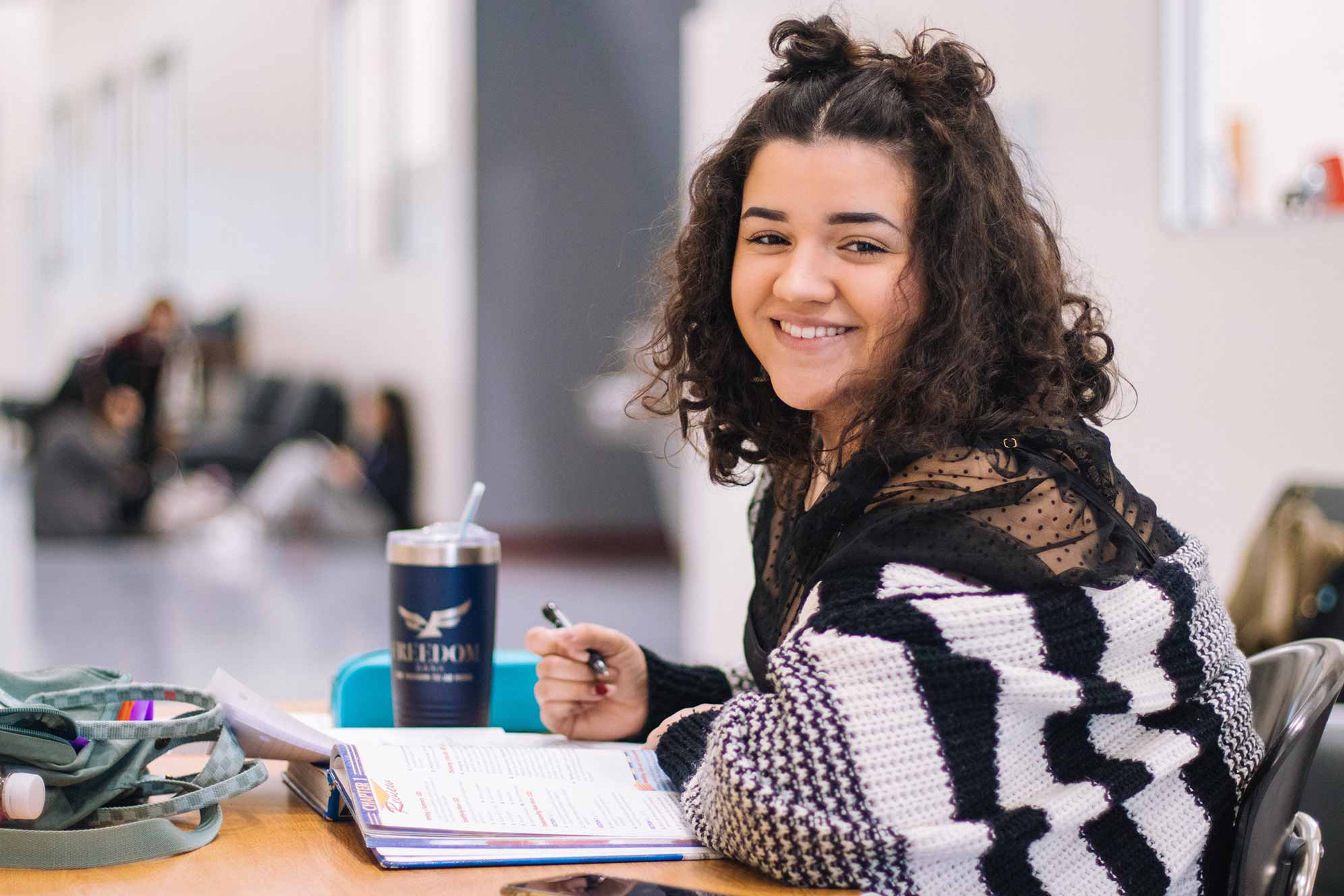 student taking notes and smiling at camera