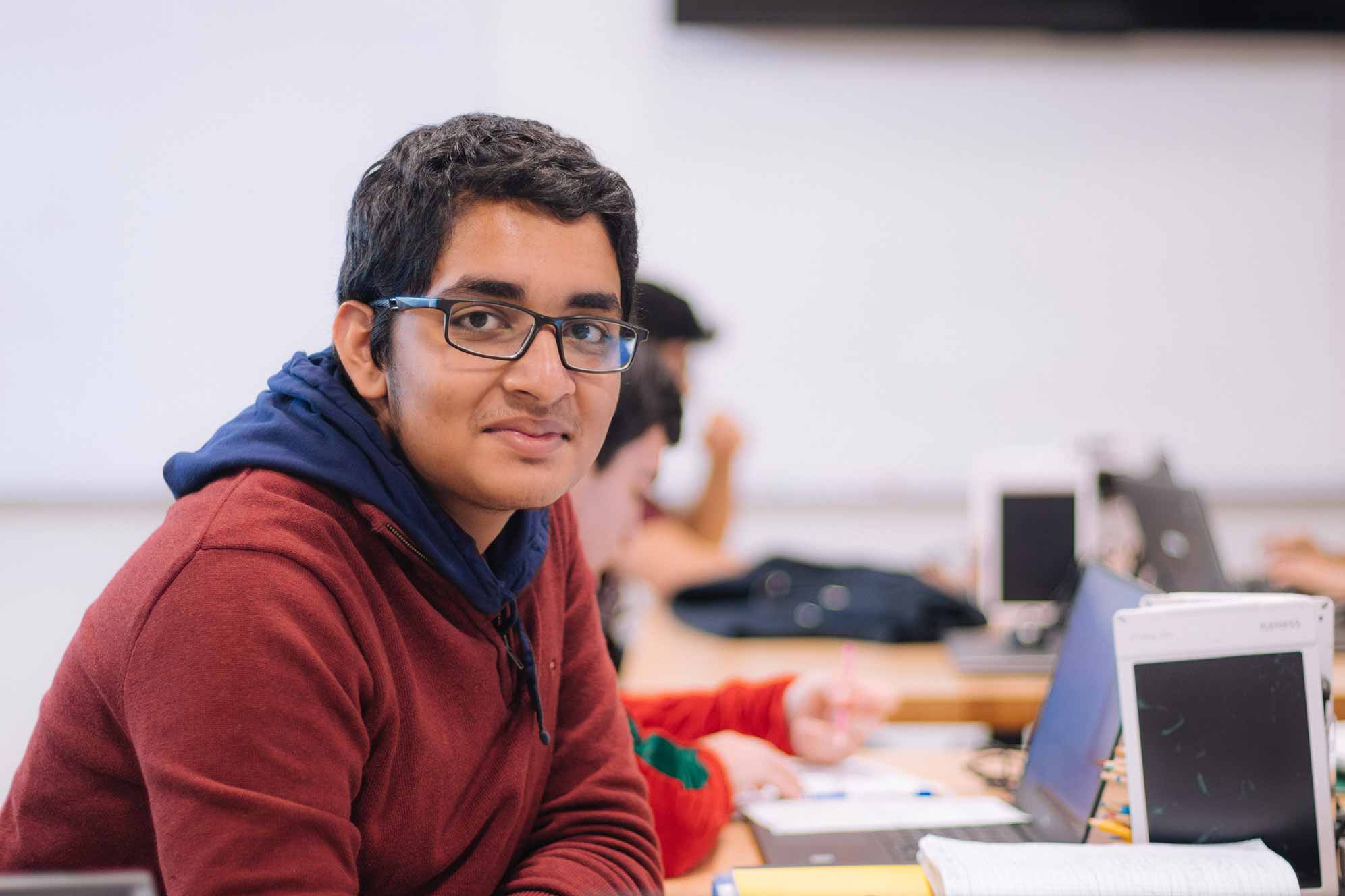 student taking notes and smiling at camera